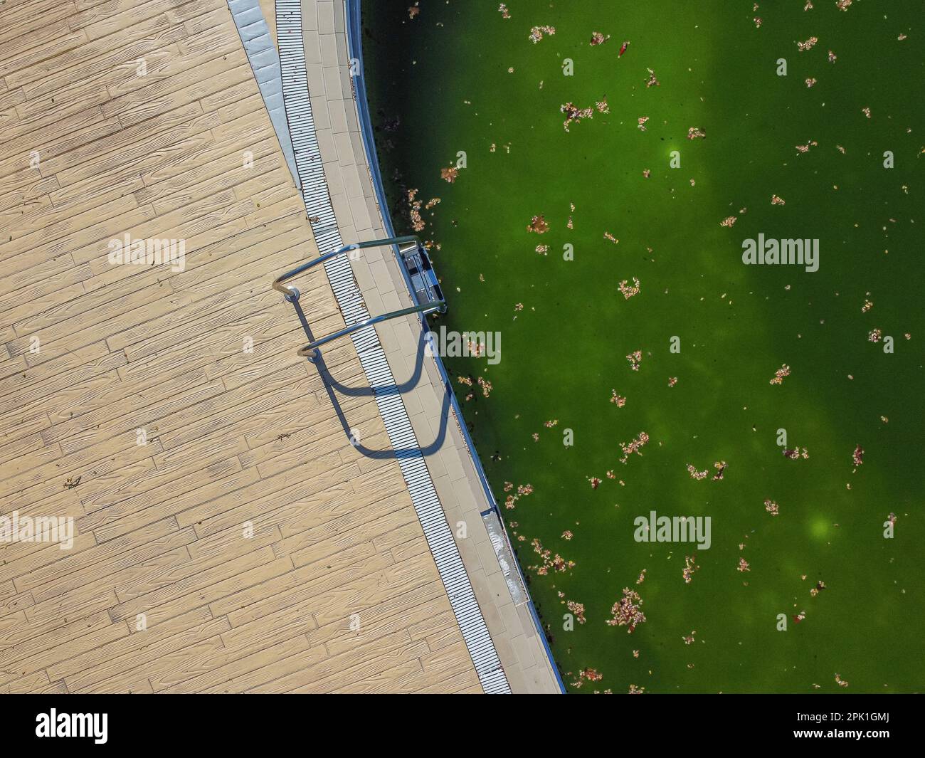 Draufsicht auf einen verlassenen Swimmingpool mit schmutzigem Wasser Stockfoto