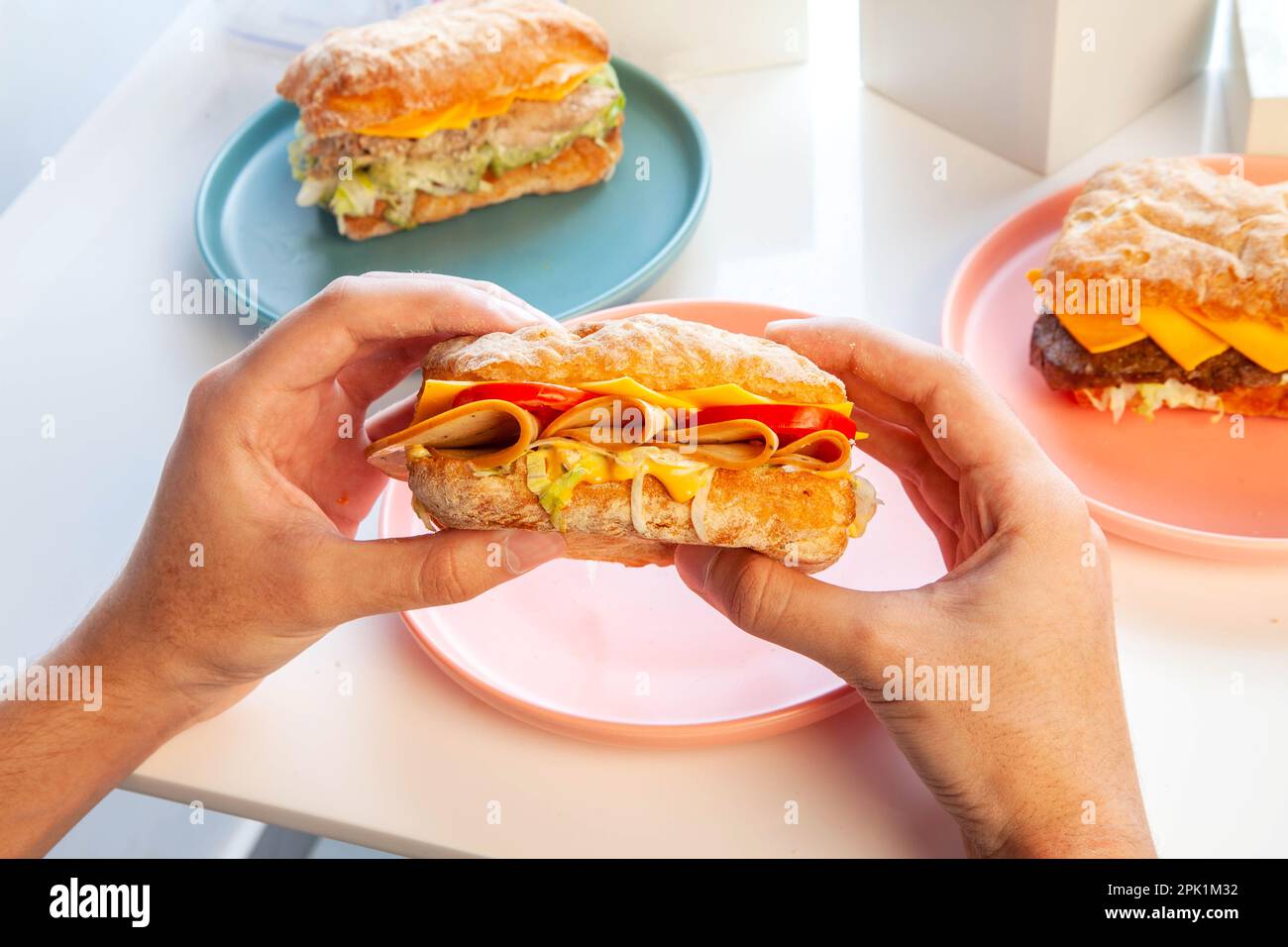 Hand haltendes Bologna-Fleisch-Ciabatta-Sandwich. Stockfoto