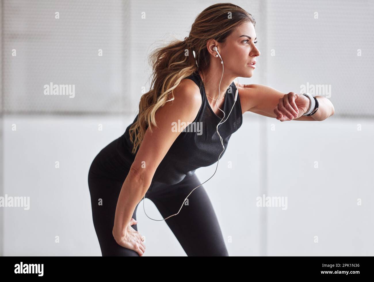 Machen Sie weiter, bis Sie gute Fortschritte machen. Eine sportliche junge Frau, die beim Sport im Freien auf ihre Uhr schaut. Stockfoto