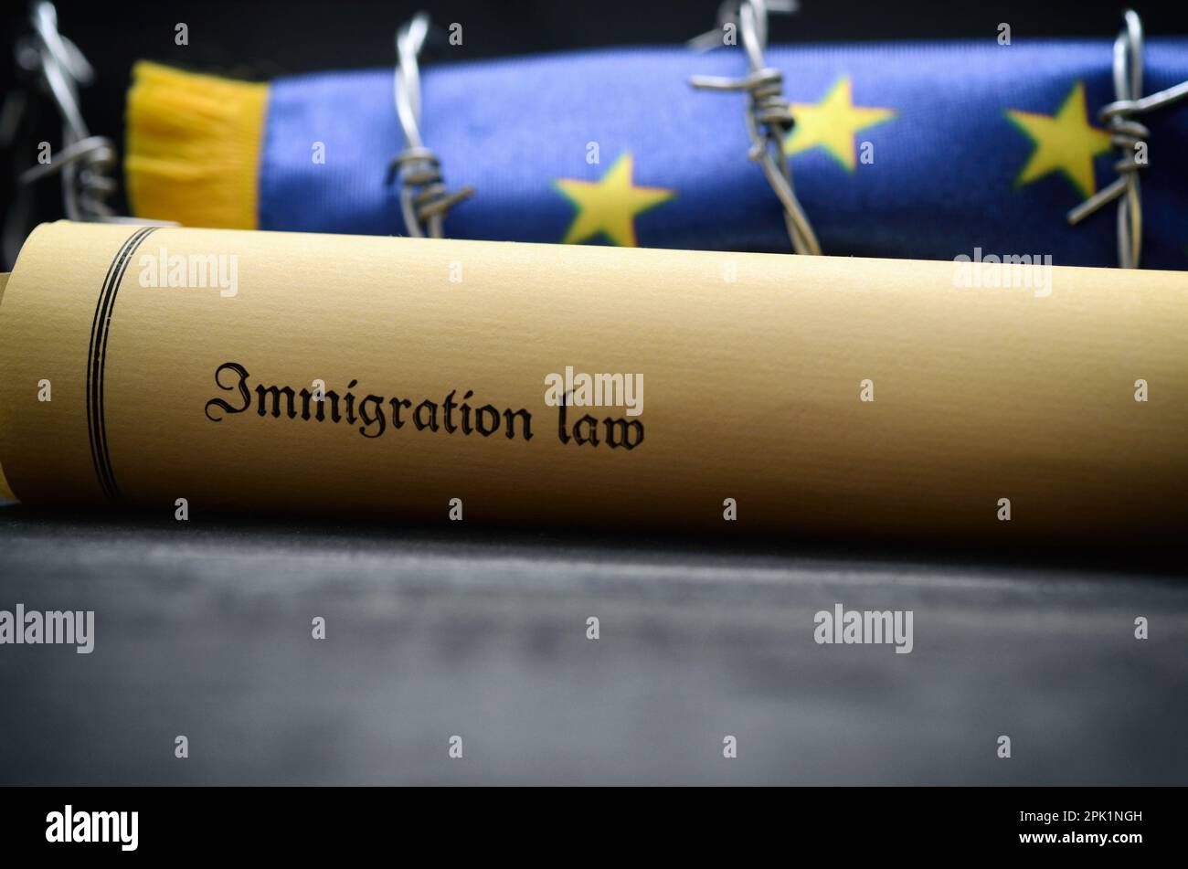 Fahne der Europäischen Union, Stacheldraht und Zuwanderungsgesetz auf schwarzem Hintergrund Holz, Migration Konzept. Stockfoto