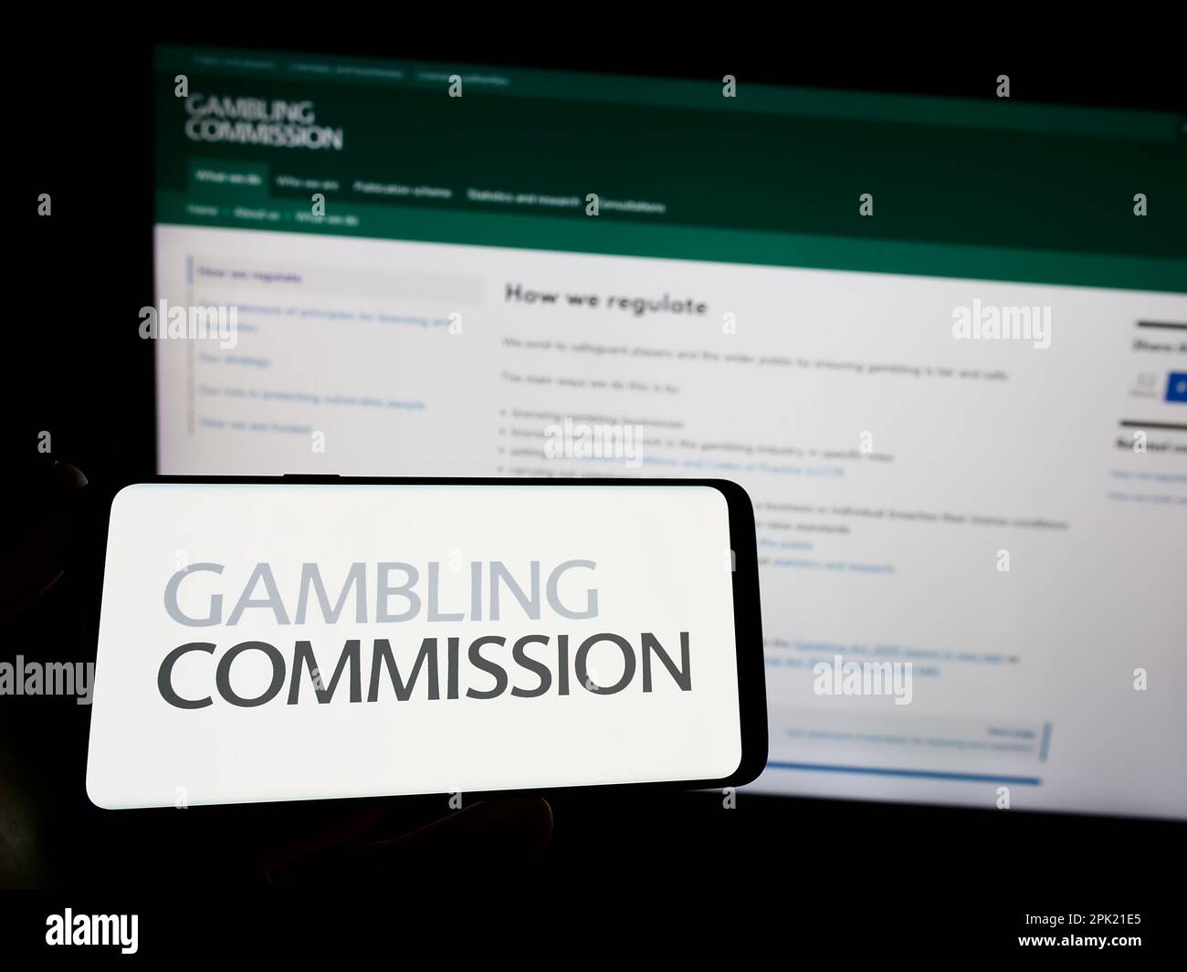 Person, die ein Smartphone mit dem Logo der britischen öffentlichen Körperschaft Gambling Commission auf dem Bildschirm vor der Website hält. Konzentrieren Sie sich auf das Display des Telefons. Stockfoto