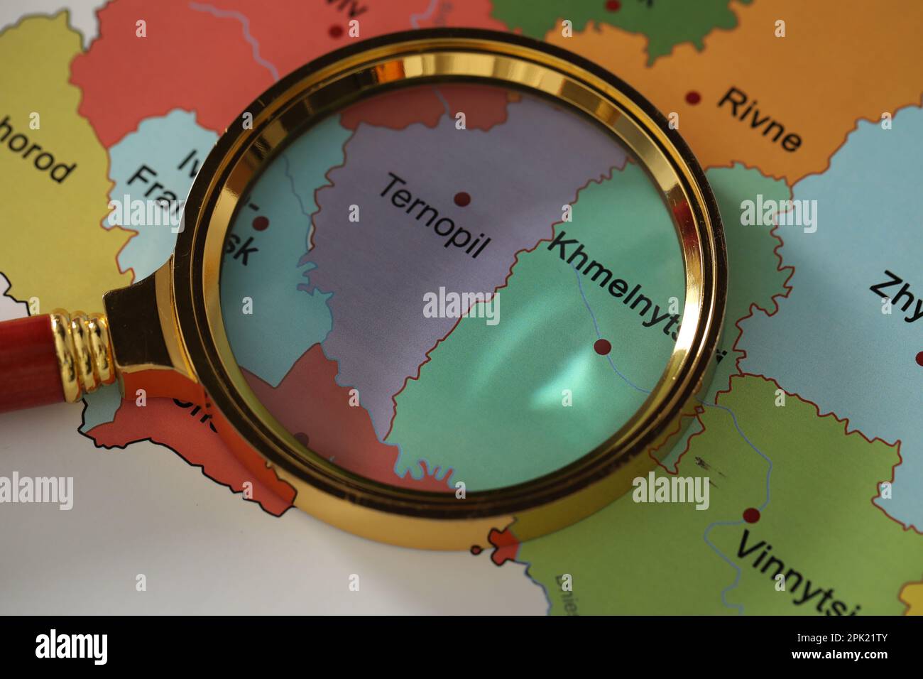 Goldenes Vergrößerungsglas über den Regionen Ternopil und Chmelnytskyi auf der Karte der Ukraine, Nahaufnahme Stockfoto
