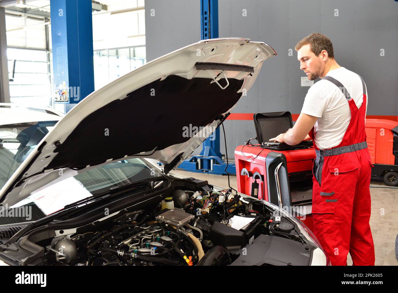 Kfz-Mechaniker prüft das Fahrzeug in einer Werkstatt - elektronische Steuergerät prüfen, Stockfoto