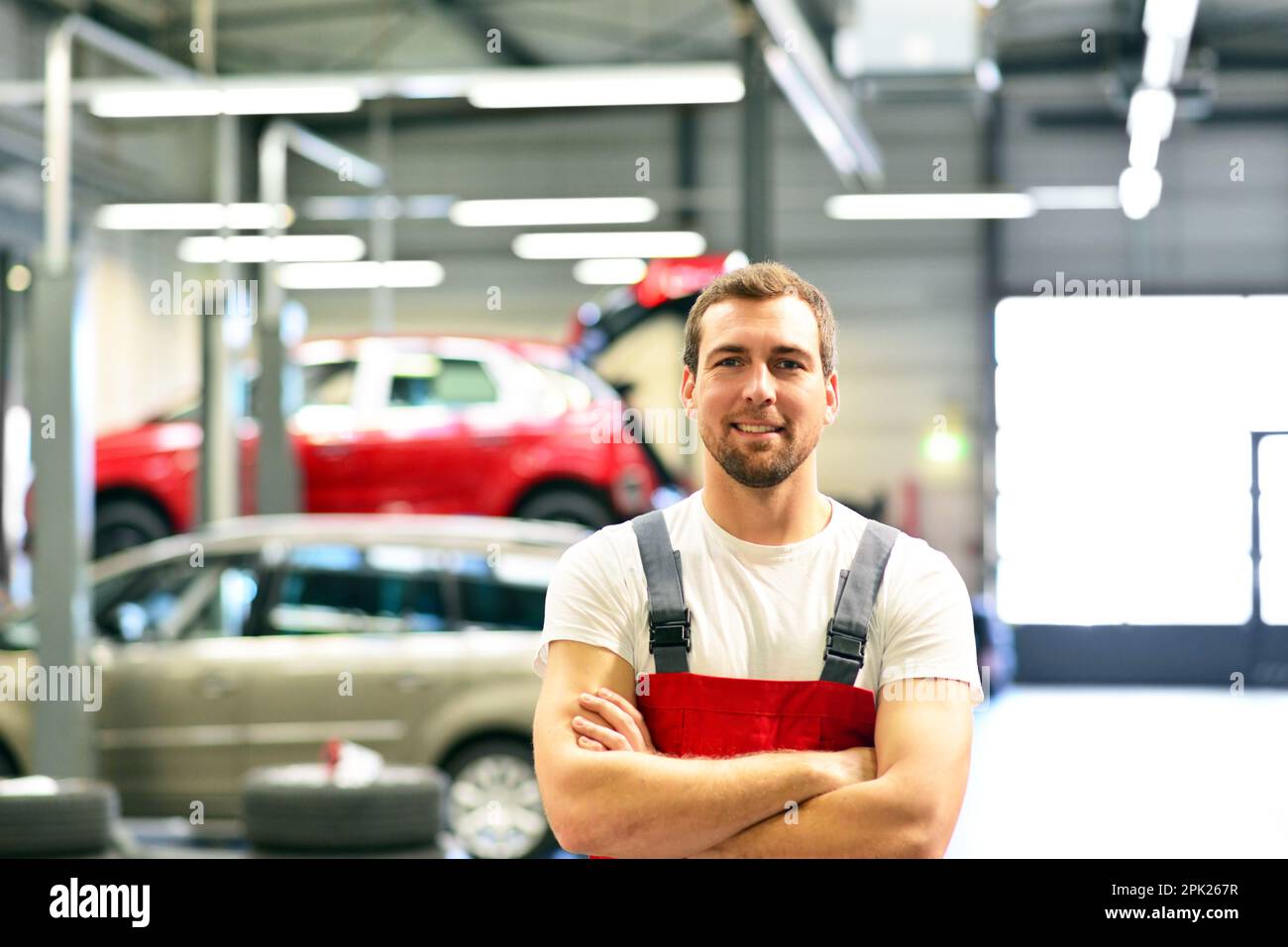 Porträt eines lächelnden Automechanikers in der Autowerkstatt in woking-Kleidung - Berufstätige Stockfoto