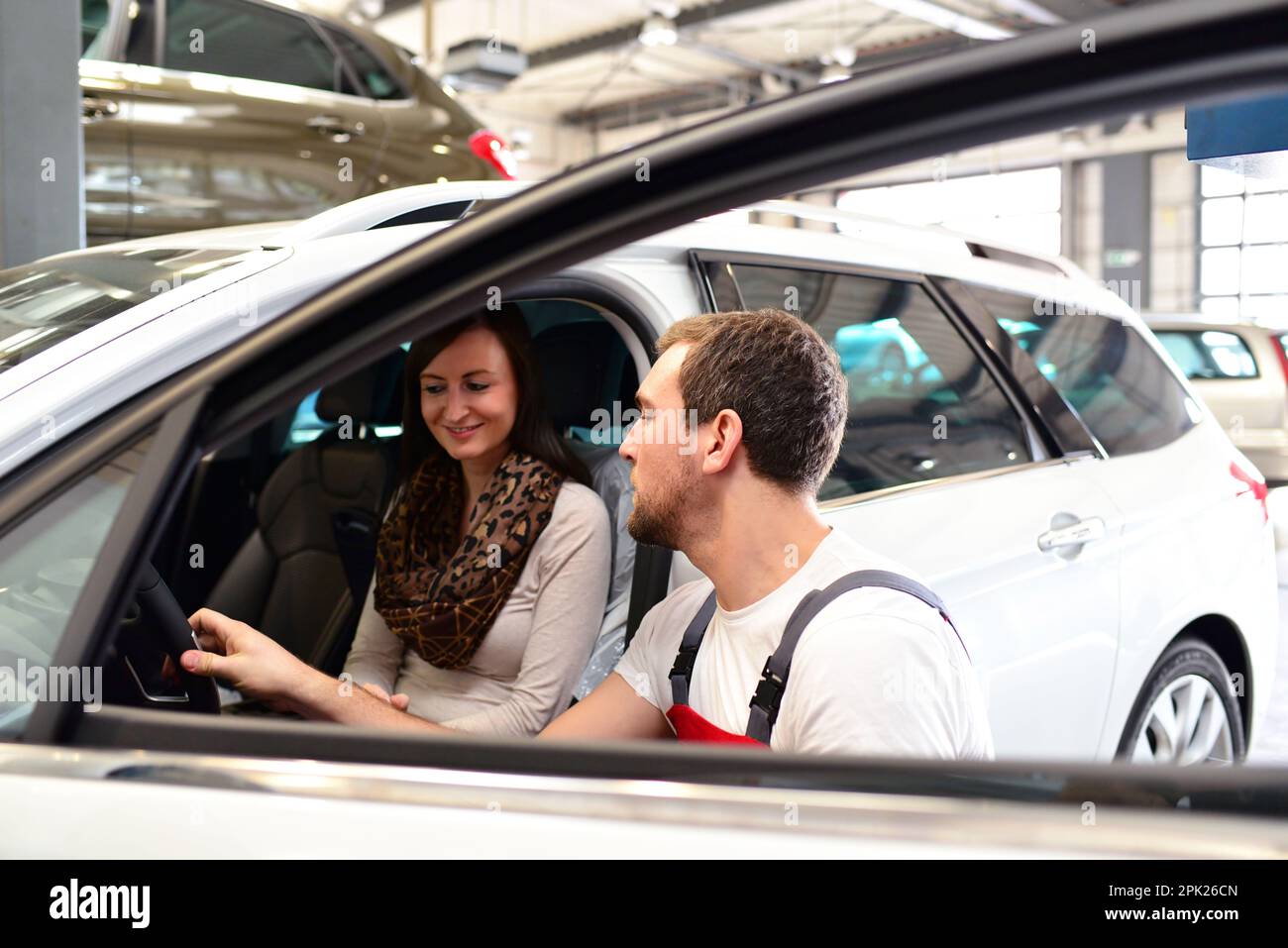 Kundendienst in einer Garage - Mechaniker und der Frau die Reparatur eines Fahrzeugs besprechen Stockfoto