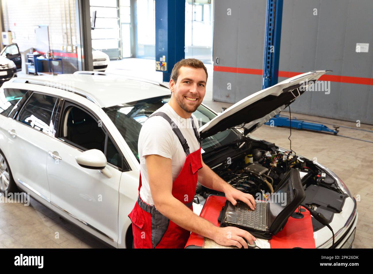 Porträt eines lächelnden Automechanikers in der Autowerkstatt in woking-Kleidung - Berufstätige Stockfoto