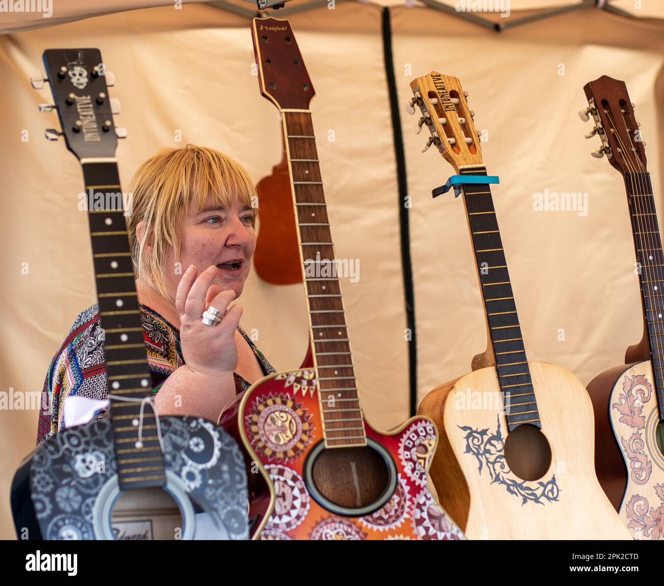 Frau, die beim Maverick Festival 2017 dekorierte Akustikgitarren verkauft Stockfoto