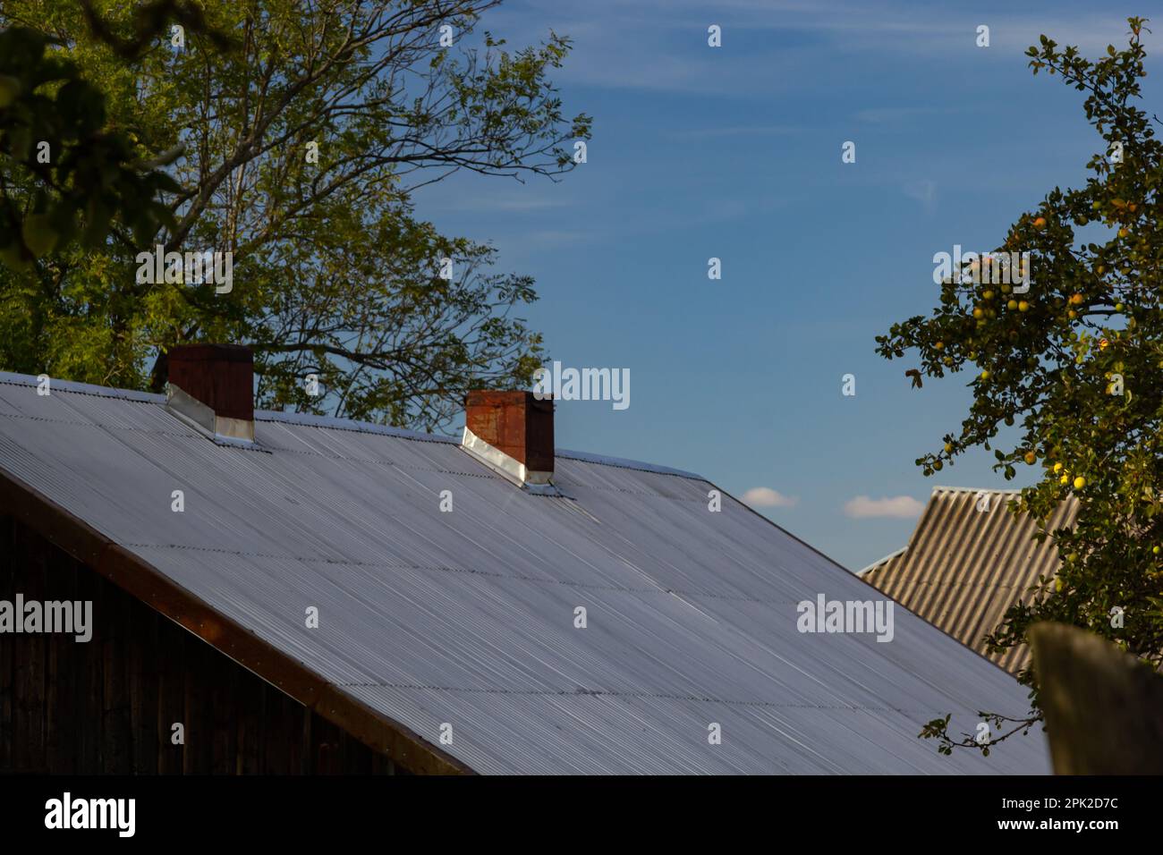 Metalldach eines Einzelhauses und Schornstein am Himmel, Dachziegel aus Metall, Dachrinnen. Stockfoto