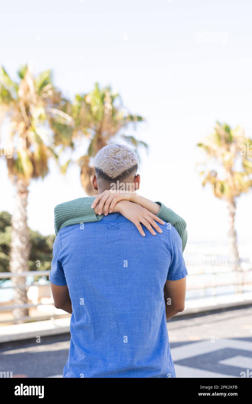 Ein vielseitiges Paar, das Zeit miteinander verbringt und die Promenade am Meer umarmt Stockfoto