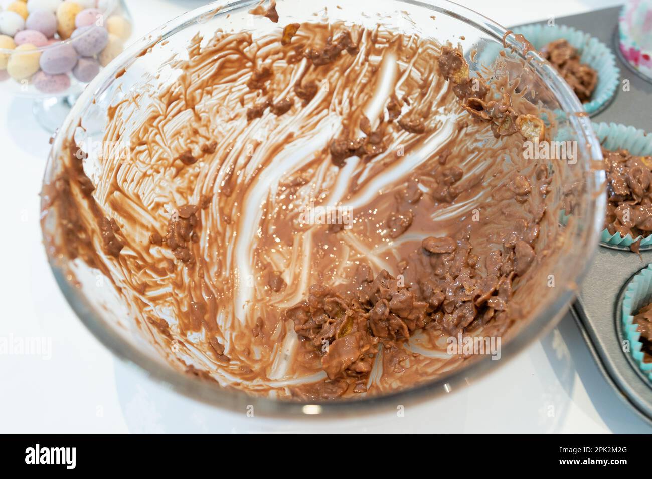 Glasschale, fast leer, mit Schokoladenkornflocken, während Sie zu Ostern Schokoladen-Mini-Eiernester zubereiten Stockfoto