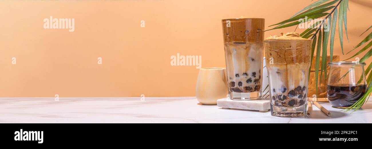 Boba dalgona Kaffee. Trendiges asiatisches Latte-Morgengetränk mit Instant-Kaffee und Tapioka-Perlkugeln, thailändisches Schaumcocktail-Glas im Sommer in der Sonne Stockfoto
