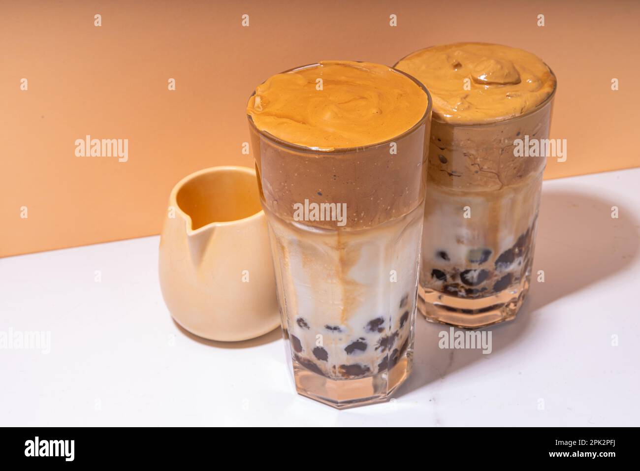 Boba dalgona Kaffee. Trendiges asiatisches Latte-Morgengetränk mit Instant-Kaffee und Tapioka-Perlkugeln, thailändisches Schaumcocktail-Glas im Sommer in der Sonne Stockfoto