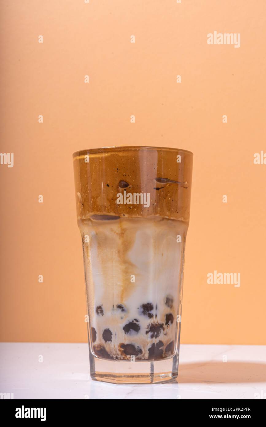 Boba dalgona Kaffee. Trendiges asiatisches Latte-Morgengetränk mit Instant-Kaffee und Tapioka-Perlkugeln, thailändisches Schaumcocktail-Glas im Sommer in der Sonne Stockfoto