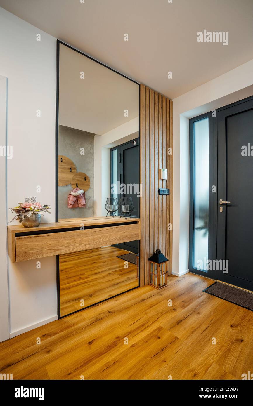 Eine hölzerne Garderobentür mit einem durchgehenden reflektierenden Spiegel im Flur neben der Eingangstür Stockfoto