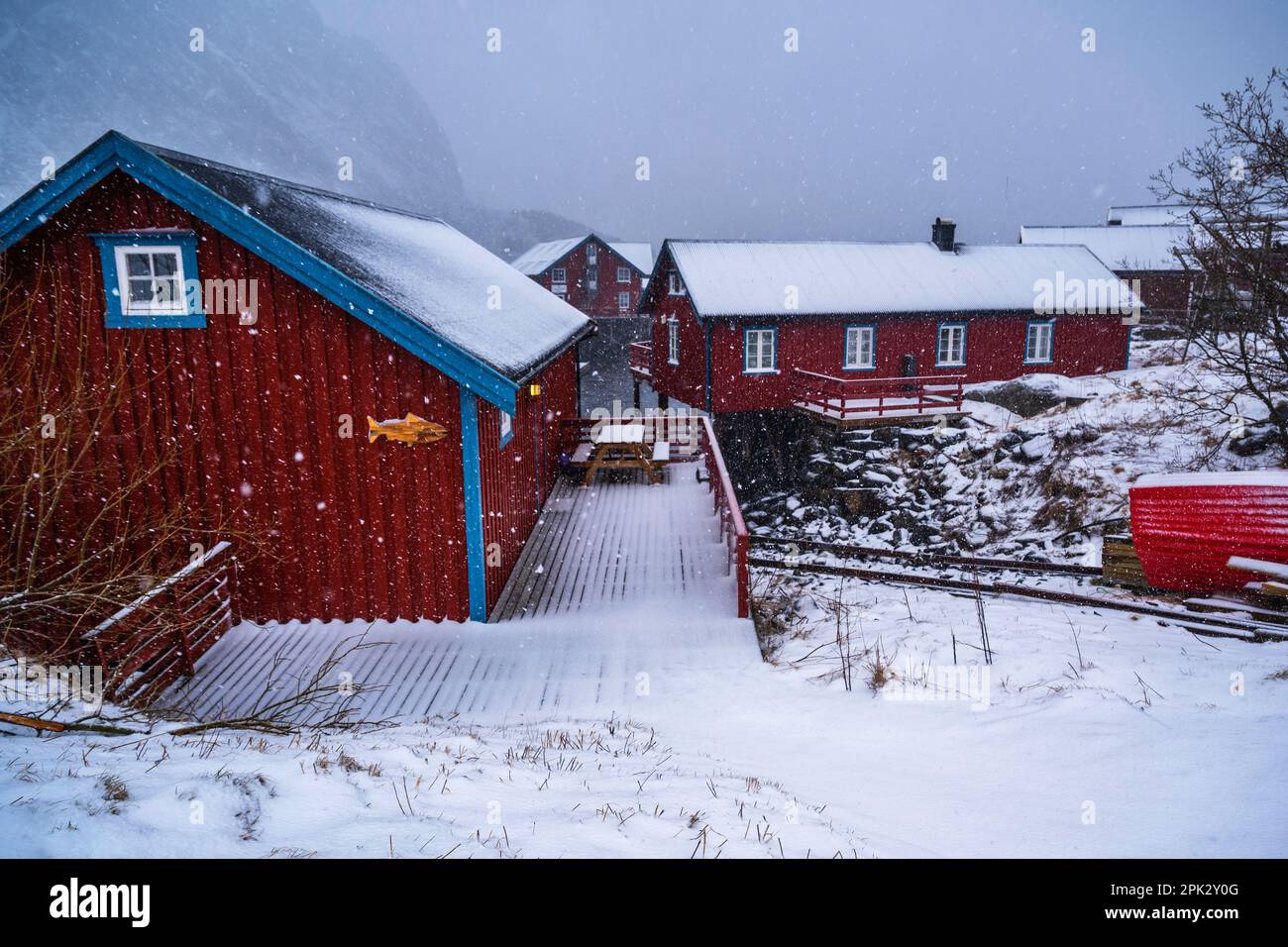 Typisches rotes Cottage (für Fischer oder Ferienunterkunft) in einem kleinen Dorf, das in dichtem Schneefall liegt. Dorf Å, Lofoten, Norwegen. Stockfoto