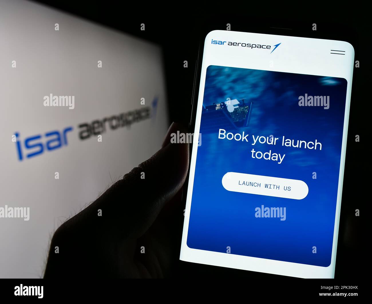 Person, die ein Mobiltelefon mit einer Webseite der Firma Isar Aerospace Technologies GmbH auf dem Bildschirm vor dem Logo hält. Konzentrieren Sie sich auf die Mitte des Telefondisplays. Stockfoto