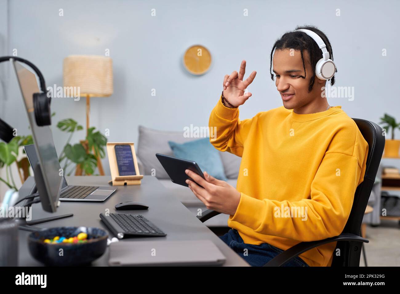 Porträt eines schwarzen jungen Mannes als Softwareentwickler, der am Arbeitsplatz ein digitales Tablet benutzt und lächelt Stockfoto
