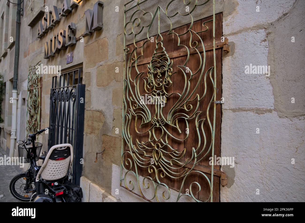 Ein alter verwitterter kunstvoll verzierter Fensterschutz aus Metall in einem verlassenen Museum afrikanischer und asiatischer Kultur in der Altstadt von Genf Stockfoto
