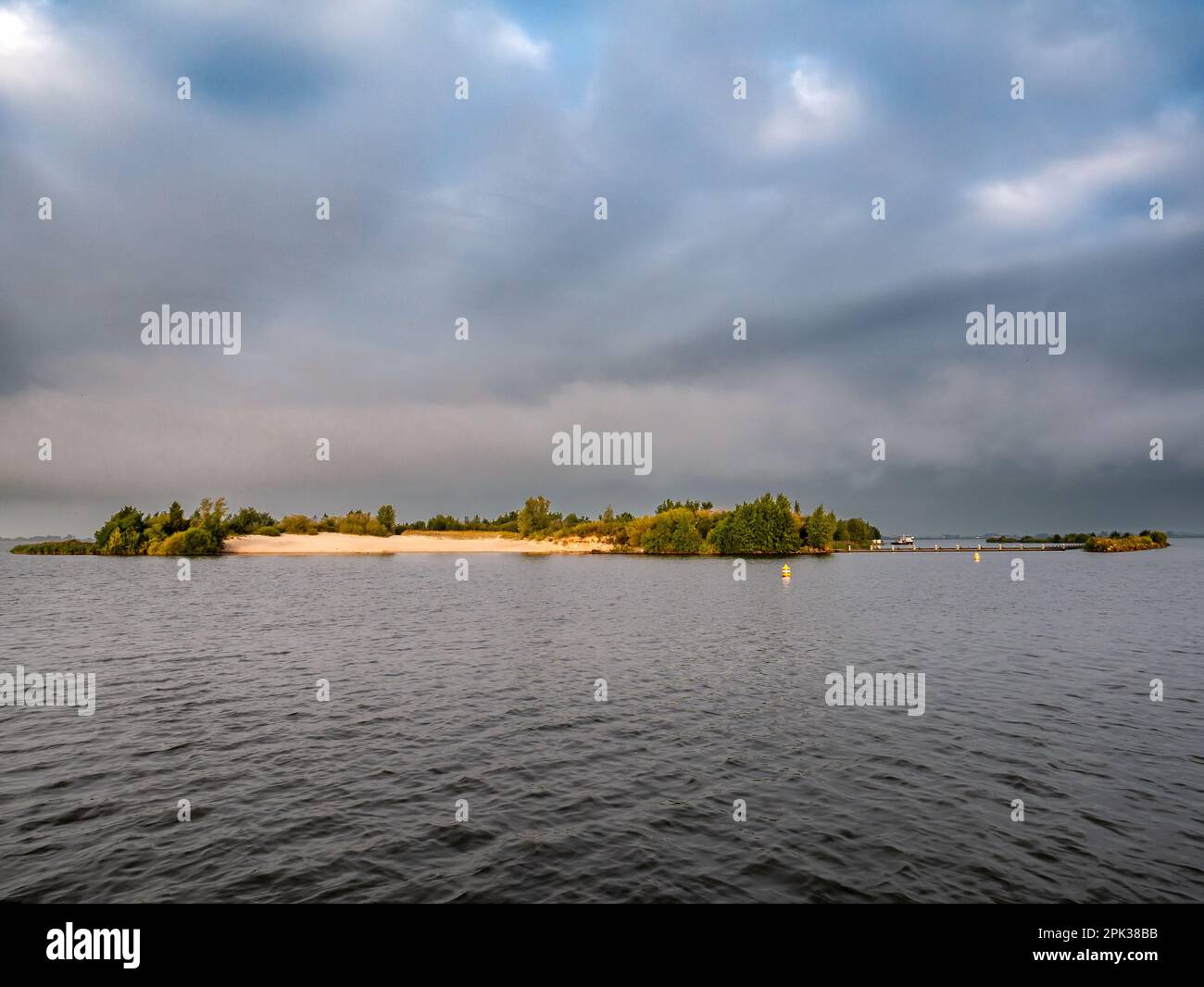Dunkle Wolken über dem Wasser und Insel des Tjeukemeer-Sees im friesischen Seengebiet, Friesland, Niederlande Stockfoto