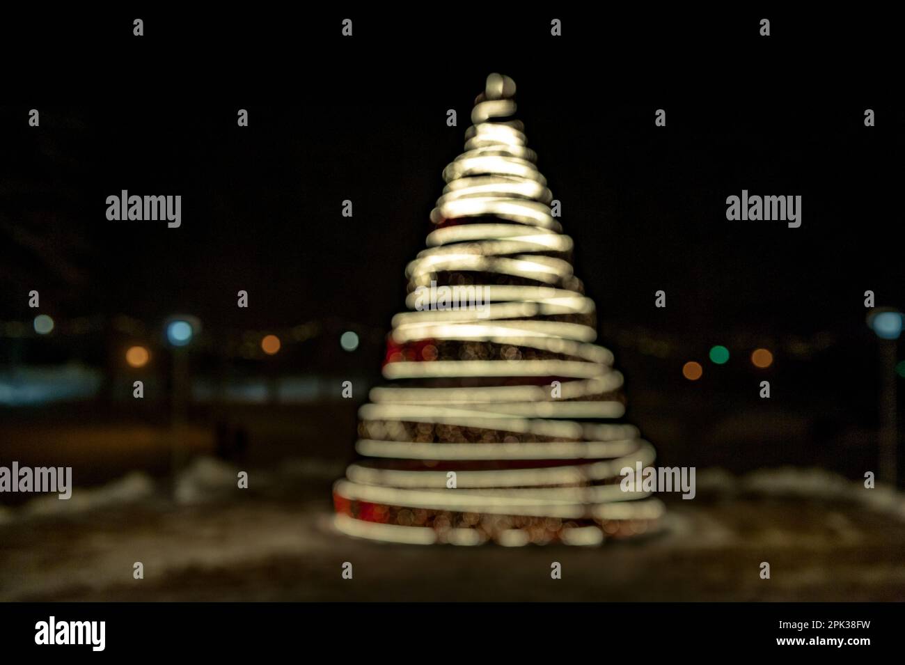 Unschärfe-Lichter spiralförmigen Weihnachtsbaum mit Bokeh auf dunklem Hintergrund. Neues Jahr. Stockfoto