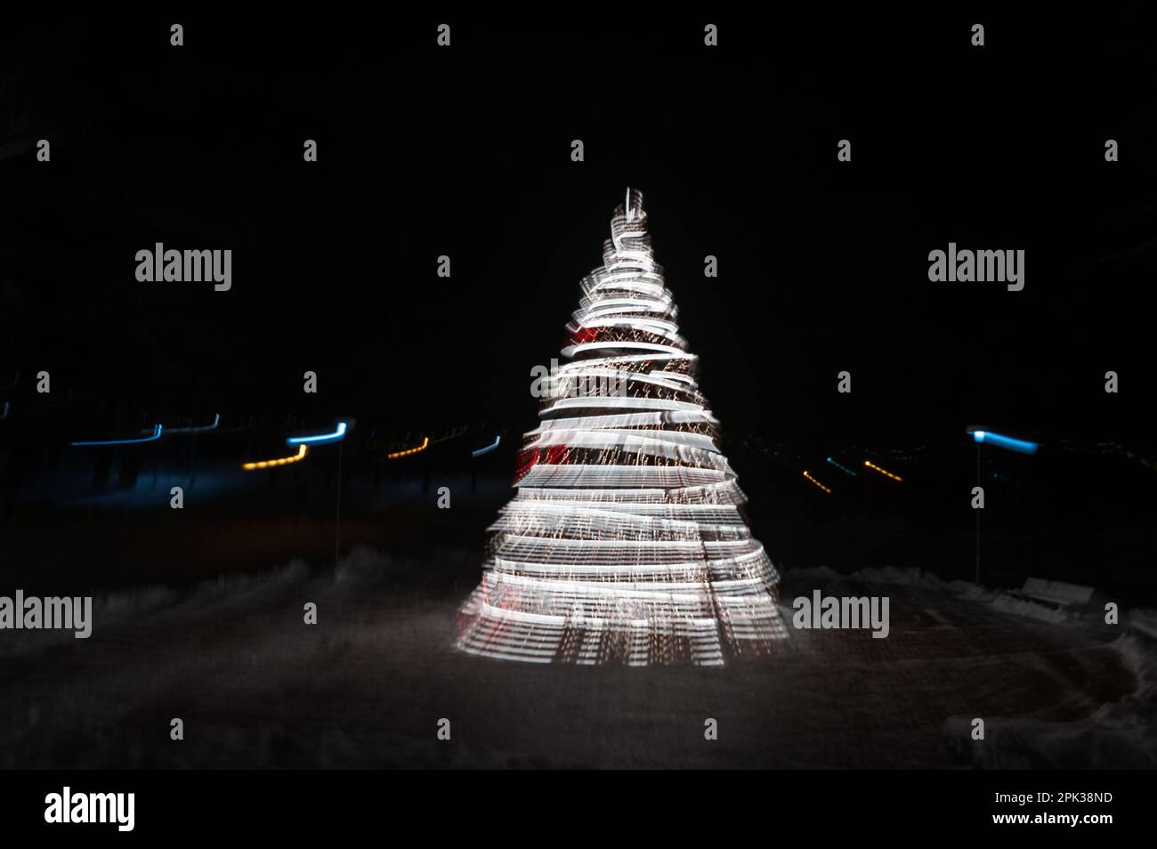 Unschärfe-Lichter spiralförmigen Weihnachtsbaum mit Bokeh auf dunklem Hintergrund. Neues Jahr. Stockfoto