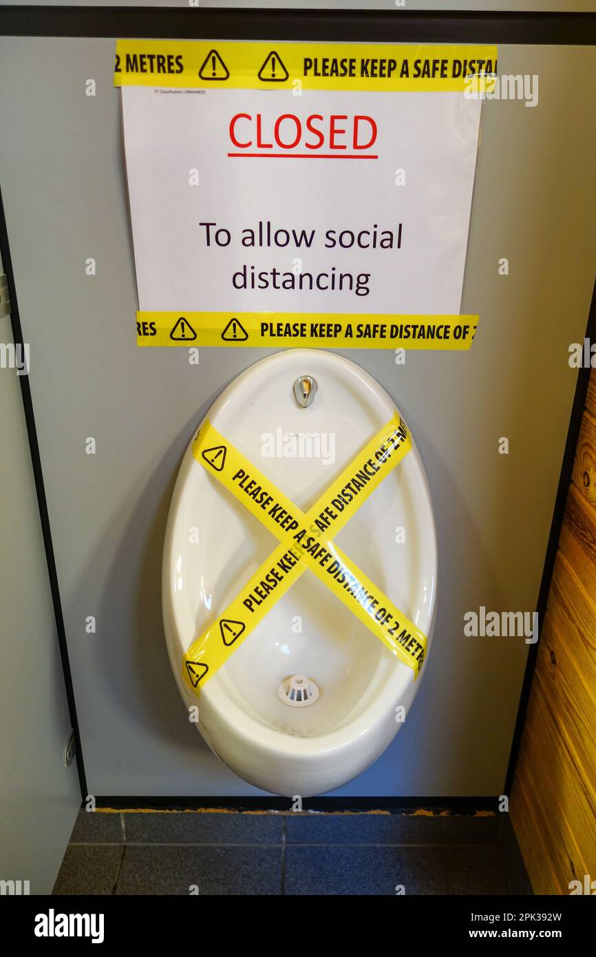 Ein Urinal in einer Herrentoilette, das mit Klebeband verschlossen wurde, um soziale Distanz zu ermöglichen, England, Großbritannien Stockfoto