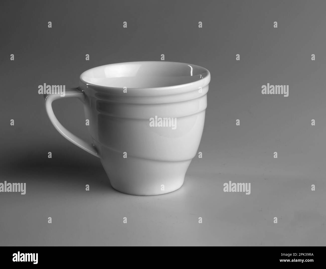 Weiße Tasse auf grauem Hintergrund. Seitenansicht. Stockfoto