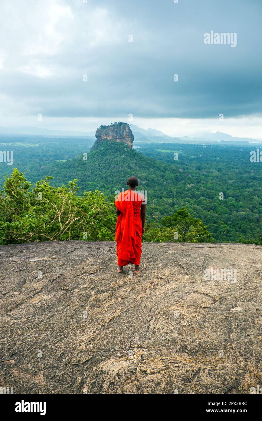 Ein buddhistischer Mönch auf dem Pidurangala Rock mit Blick auf den Löwenfelsen in Sigiriya ( oder Sinhagiri ) in Sri Lanka Stockfoto