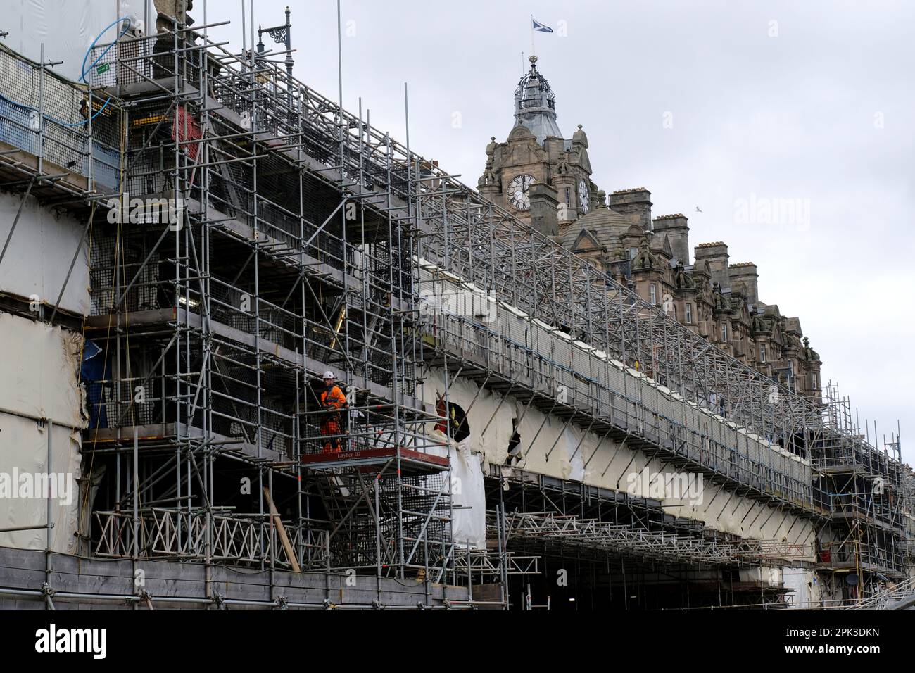 Edinburgh, Schottland, Großbritannien. 5. April 2023 Es wurde angekündigt, dass die berühmte North Bridge in Richtung Norden im April wieder geöffnet wird, nachdem 2 Jahre lang nur eine Fahrspur in Richtung Süden gefahren wurde, was zu einer Unterbrechung der Verbindung zwischen der Altstadt und der Princes Street und dem größeren Gebiet von New Town führt. Es wurde 2021 geschlossen, da es zum ersten Mal seit den 1930er Jahren wesentliche Arbeiten durchlaufen hat. Das Projekt liegt bereits fünf Jahre hinter dem Zeitplan zurück und hat sein Budget auf £62 Millionen Dollar mehr als verdoppelt. Die Brücke ist mit Gerüsten verkleidet und blickt mit einem Arbeiter nach Norden in Richtung Balmoral Hotel. Kredit: Craig Brown/Alamy Live News Stockfoto