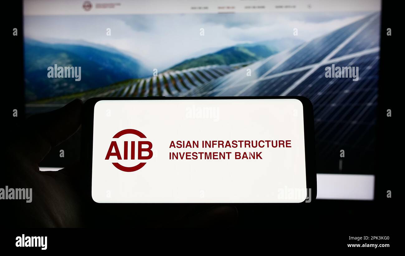 Person, die ein Smartphone mit dem Logo der Asiatischen Infrastruktur-Investitionsbank (AIIB) auf dem Bildschirm vor der Website hält. Konzentrieren Sie sich auf das Display des Telefons. Stockfoto