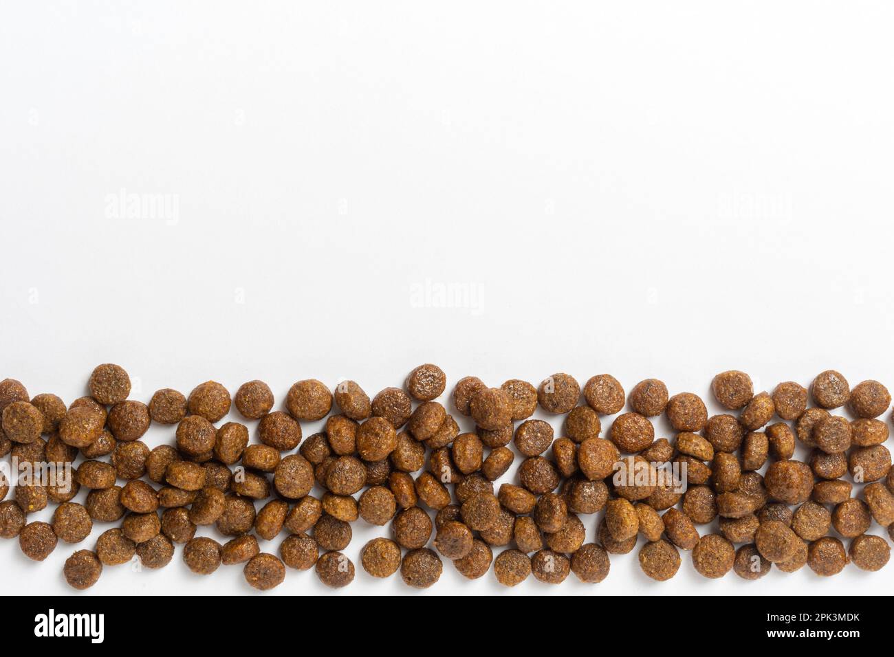 Hintergrund von trockenem Haustierfutter. Ein Haufen granuliertes Tierfutter auf Weiß. Granulat mit guter Ernährung für Hunde und Katzen. Stockfoto