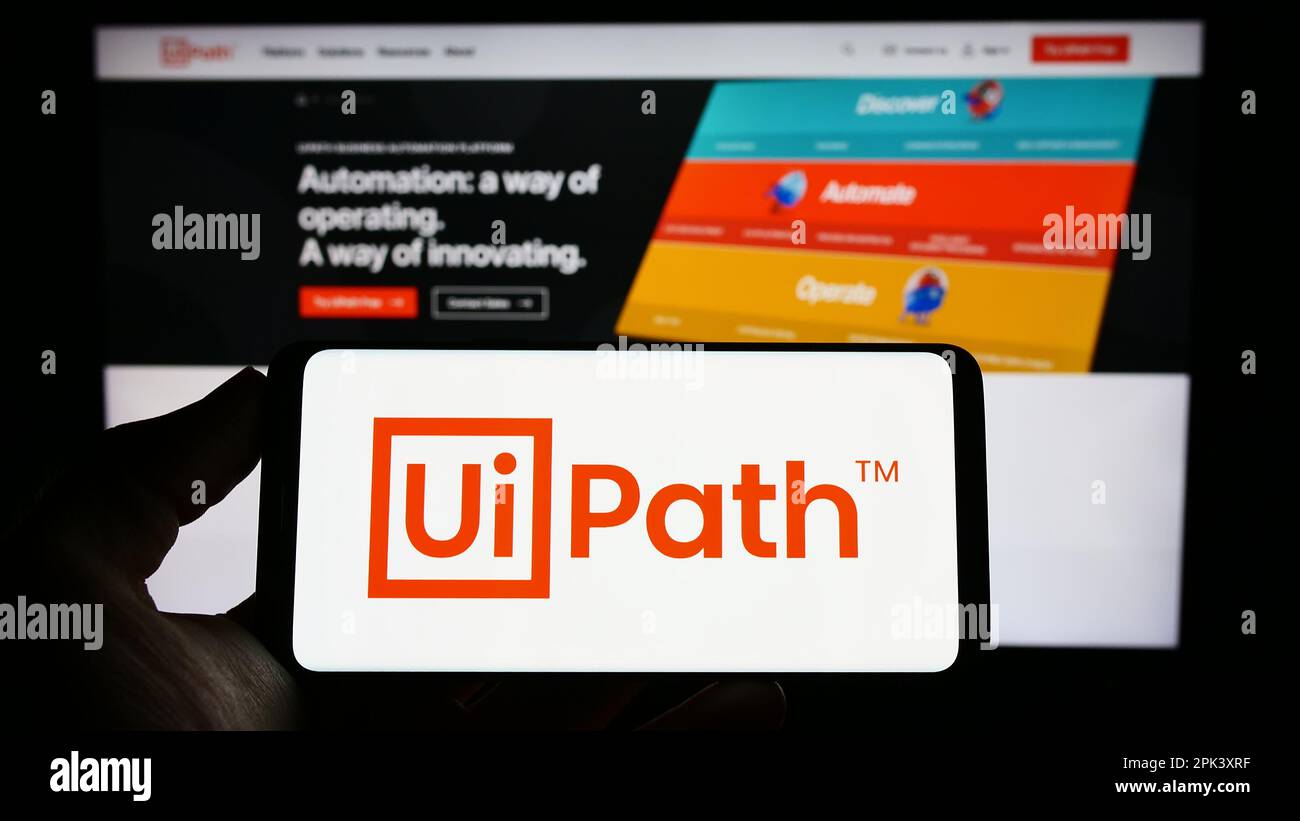 Person, die ein Mobiltelefon mit dem Logo des Automationssoftwareunternehmens UiPath Inc. Auf dem Bildschirm vor der Unternehmenswebseite hält. Konzentrieren Sie sich auf das Display des Telefons. Stockfoto