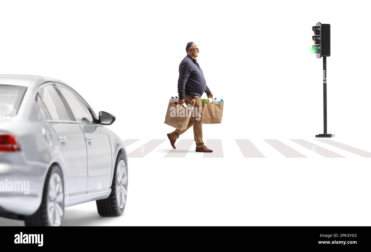 Ein Auto nähert sich auf der Straße und ein erwachsener Mann, der Einkaufstüten trägt und bei einem Fußgängerzebra isoliert auf weißem Hintergrund überquert Stockfoto