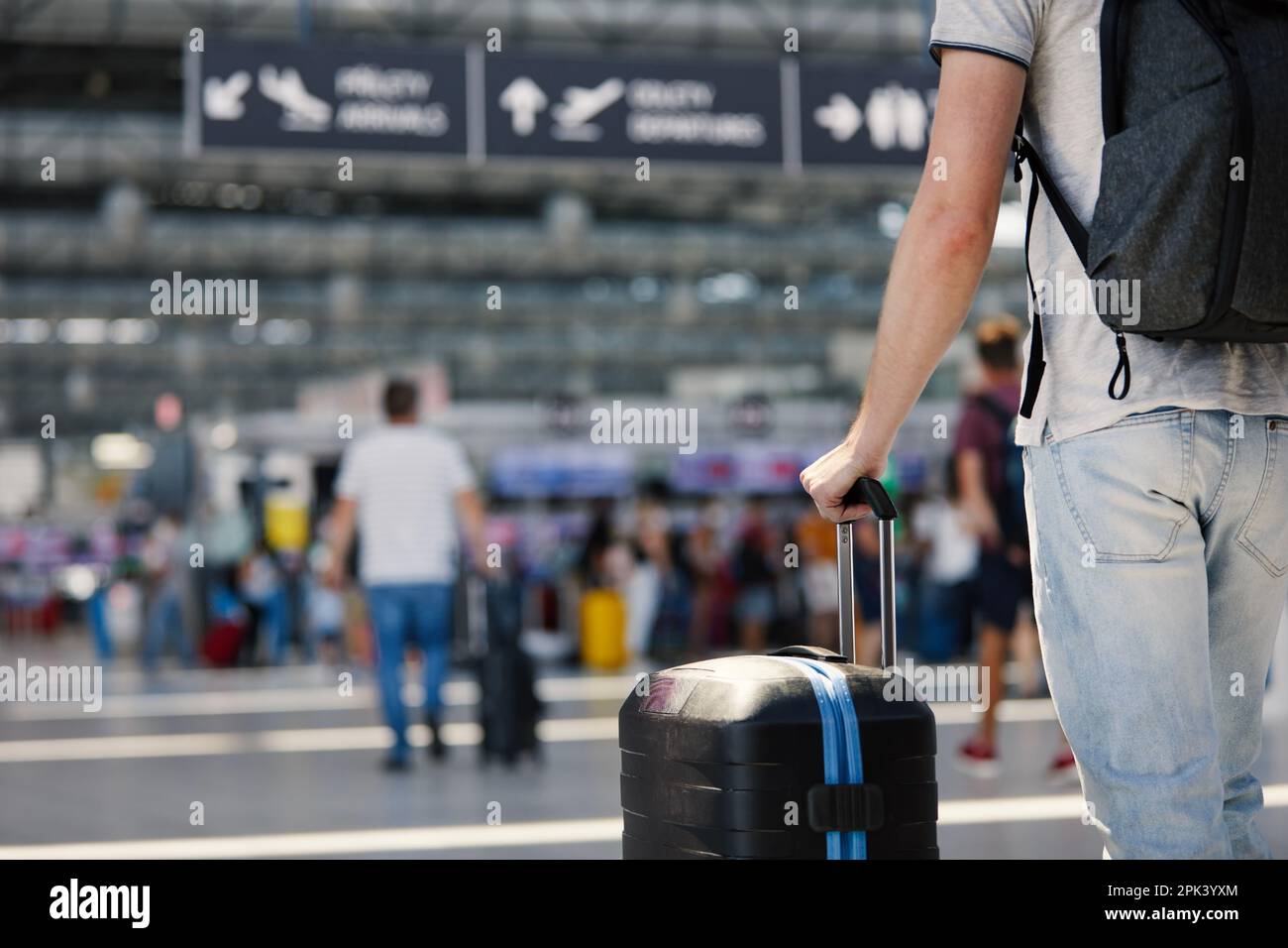 Reisen mit dem Flugzeug. Selektiver Fokus auf die Hand des Mannes, der Koffer hält. Reisende, die mit Gepäck durch den Flughafenterminal zum Check-in gehen. Stockfoto