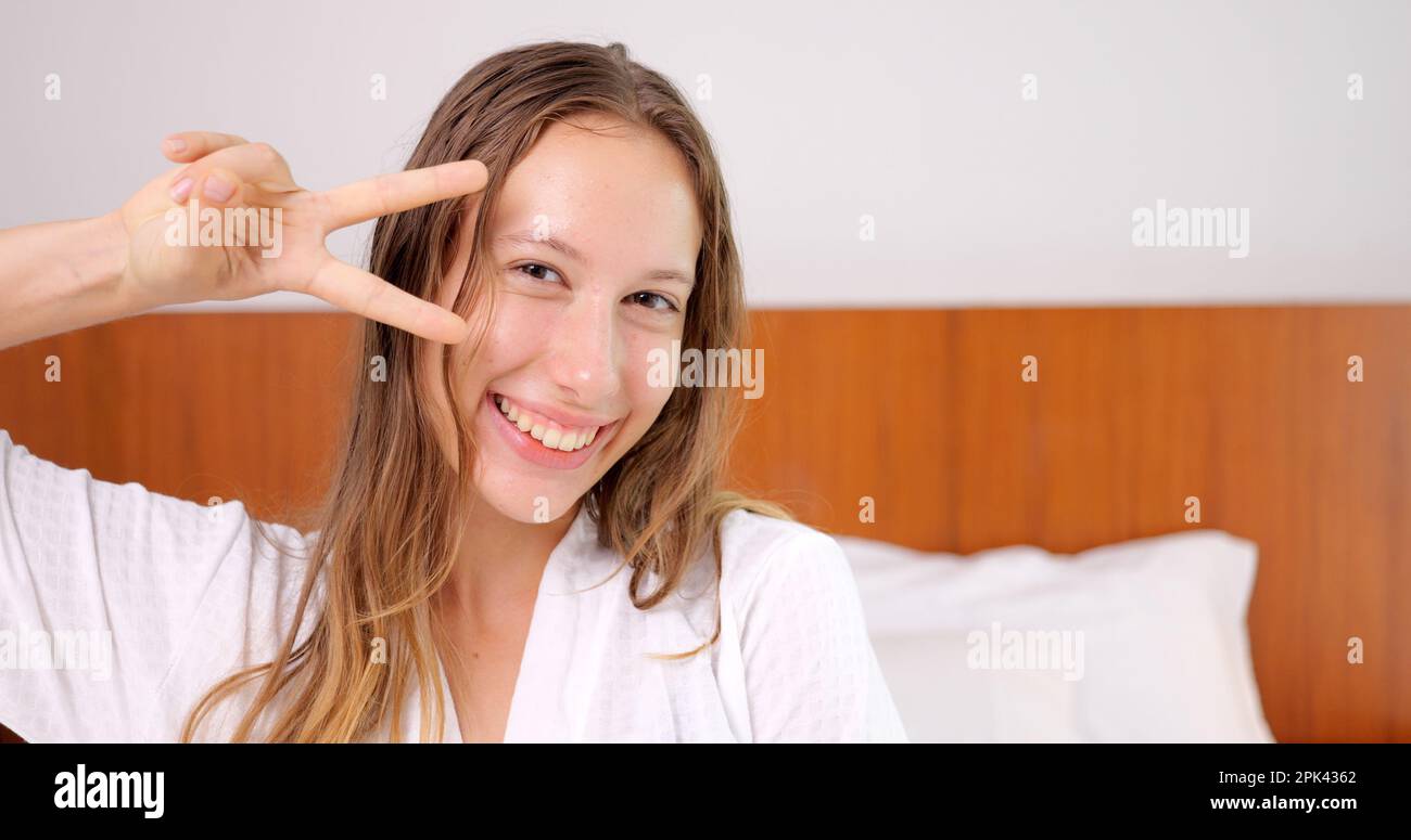 Porträt einer jungen, prächtigen, lächelnden Frau im weißen Bademantel, die in die Kamera schaut Stockfoto