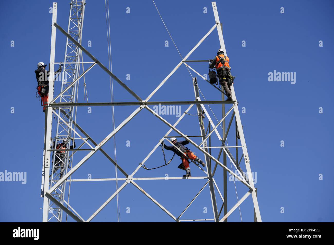 Elektriker arbeiten über Kopf, um einen Hochspannungspylon zum Austausch zu zerlegen. Mailand, Italien - April 2023 Stockfoto