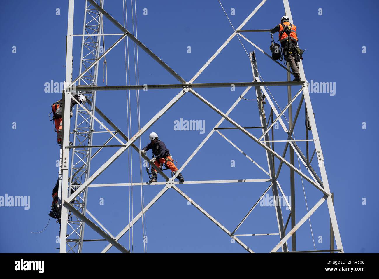 Elektriker arbeiten über Kopf, um einen Hochspannungspylon zum Austausch zu zerlegen. Mailand, Italien - April 2023 Stockfoto