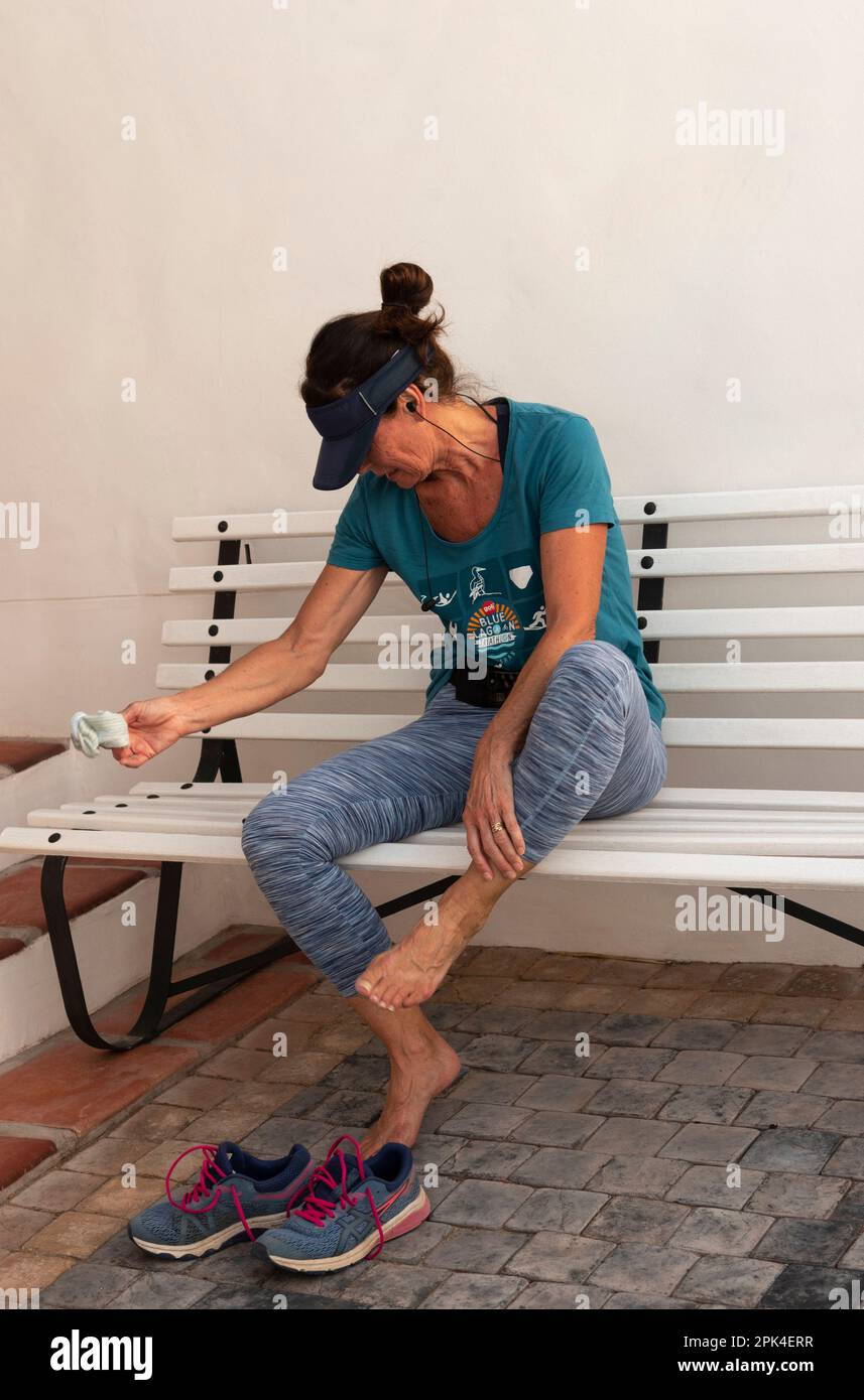 Südafrika. 2023. Aktive Frau entspannt sich und zieht nach einem Lauf ihre Socken aus. Stockfoto