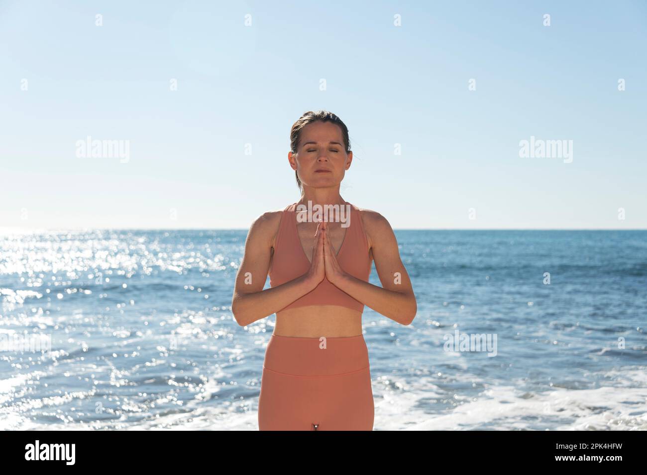Eine Frau meditiert und am Meer Yoga praktiziert, um dem Alltag zu entfliehen. Stockfoto
