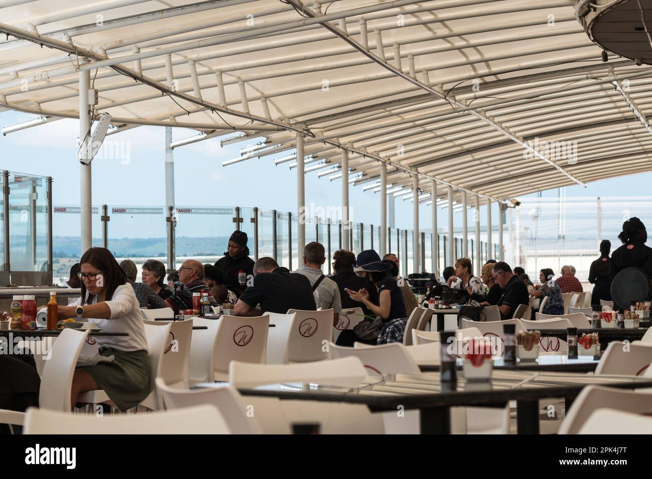 Gäste, die draußen sitzen oder im Freien in einem Café oder Restaurant am Flughafen Lanseria, Gauteng, Südafrika, speisen Stockfoto