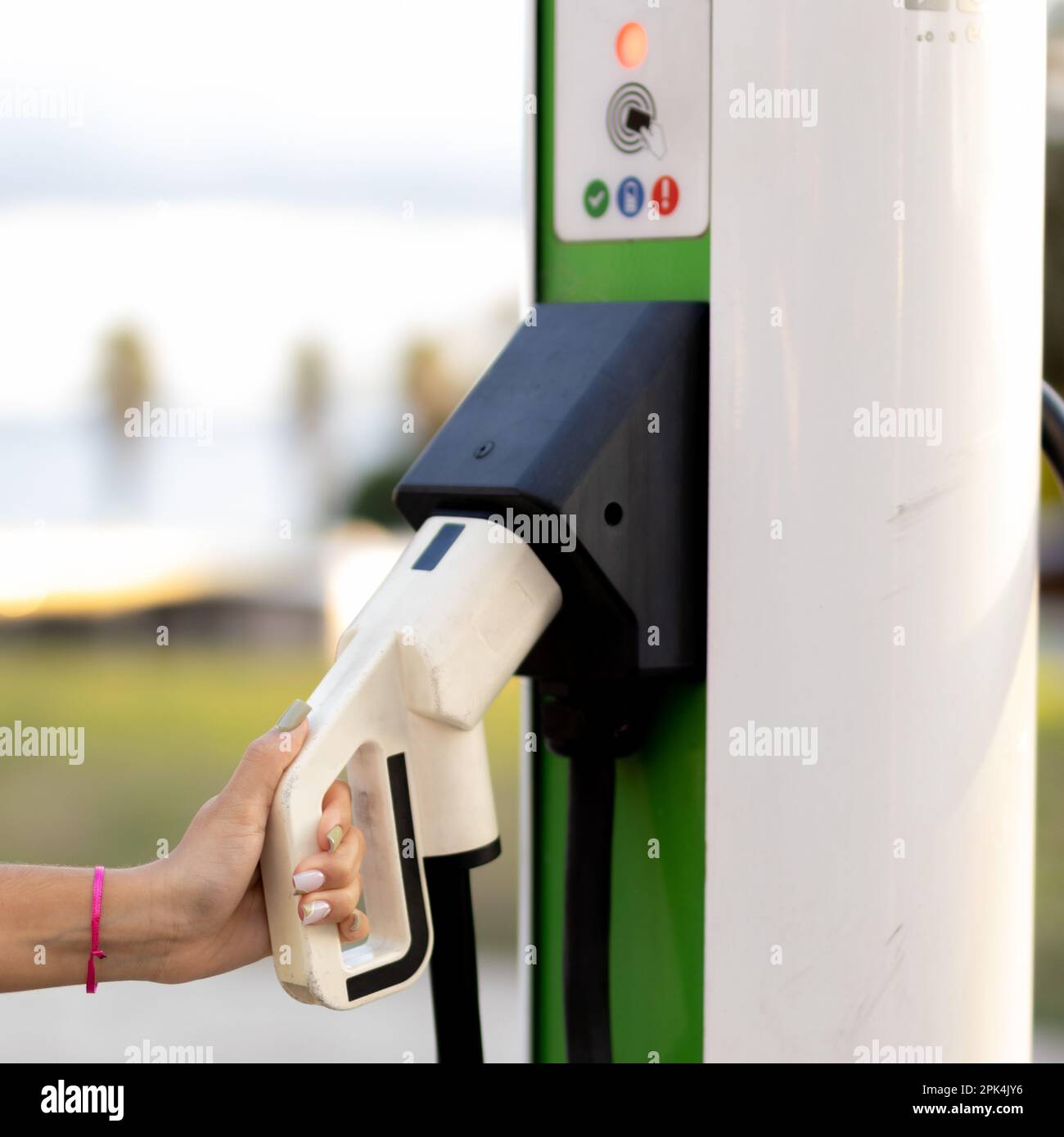Kaukasisches Teenager-Mädchen mit elektrischem Ladestecker für Elektroautos. Stockfoto