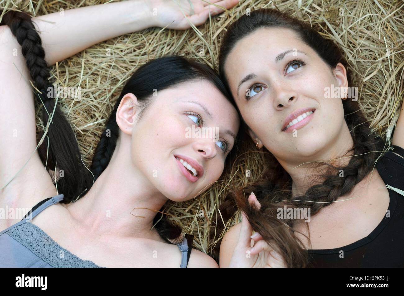 Zwei junge, schöne Frauen in stiller Kommunikation auf der Ranch am Sommertag Stockfoto