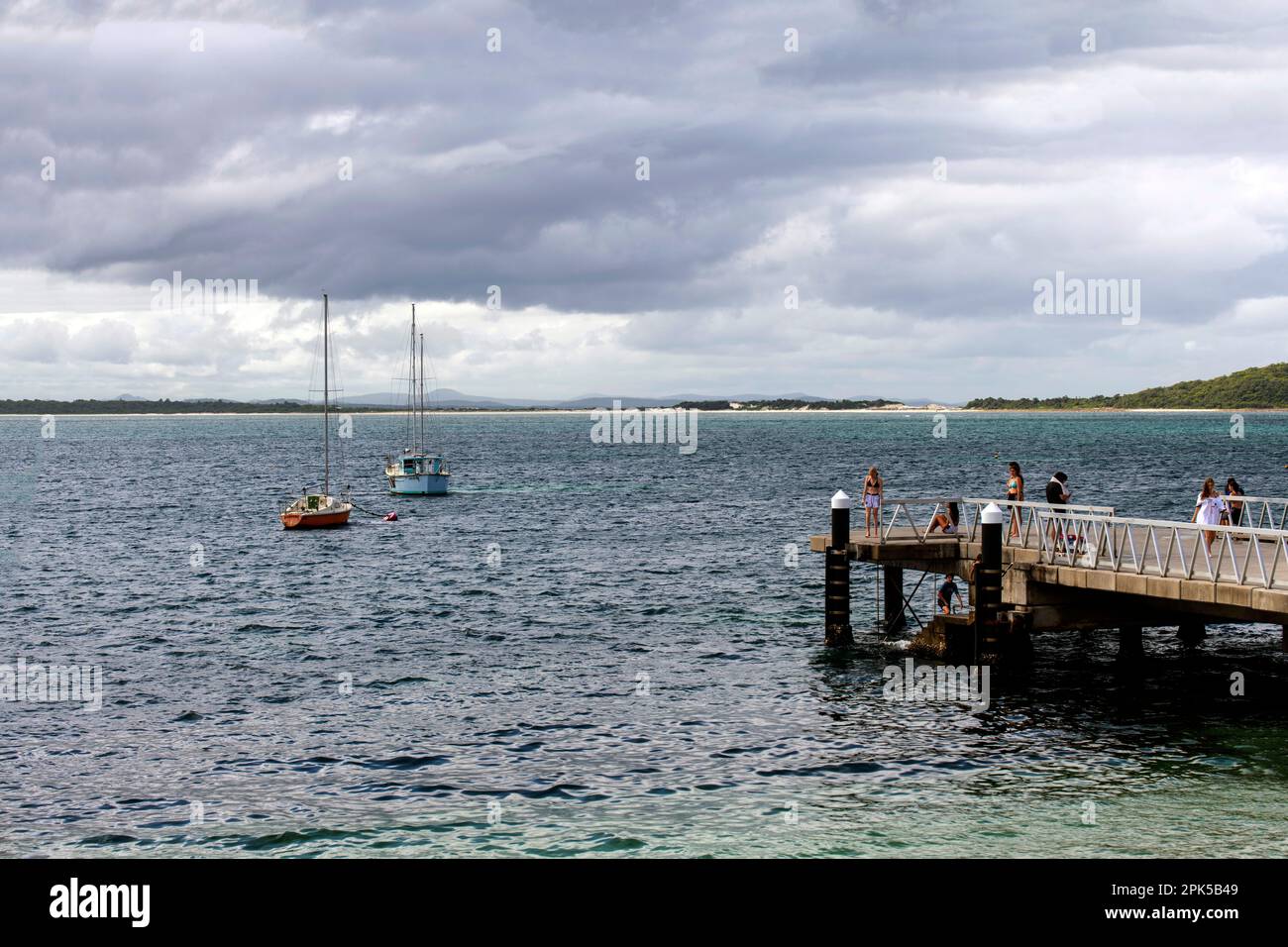 Gäste genießen Shoal Bay Beach Jetty, Port Stephens, Mid North Coast, New South Wales, Australien. Shoal Bay ist der östlichste Vorort des Hafens Stockfoto