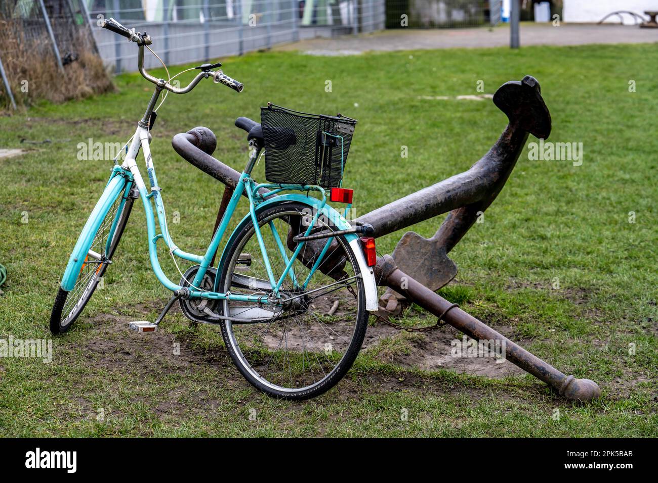 Fahrrad, Damenfahrrad, gut gesichert mit einem Fahrradschloss am Anker eines eisernen Schiffs, in Bremerhaven, Bremen, Deutschland. Stockfoto