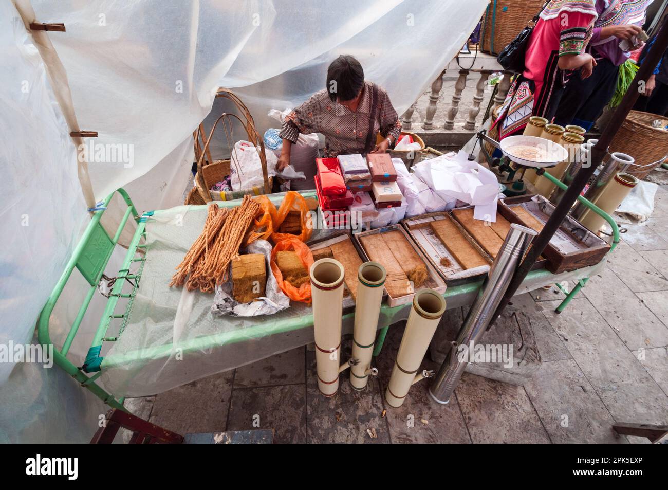 Eine Frau, die Tabakpakete zum Verkauf in einem kleinen Marktstand in der chinesischen Provinz Jianshui Yunnan verpackt hat Stockfoto