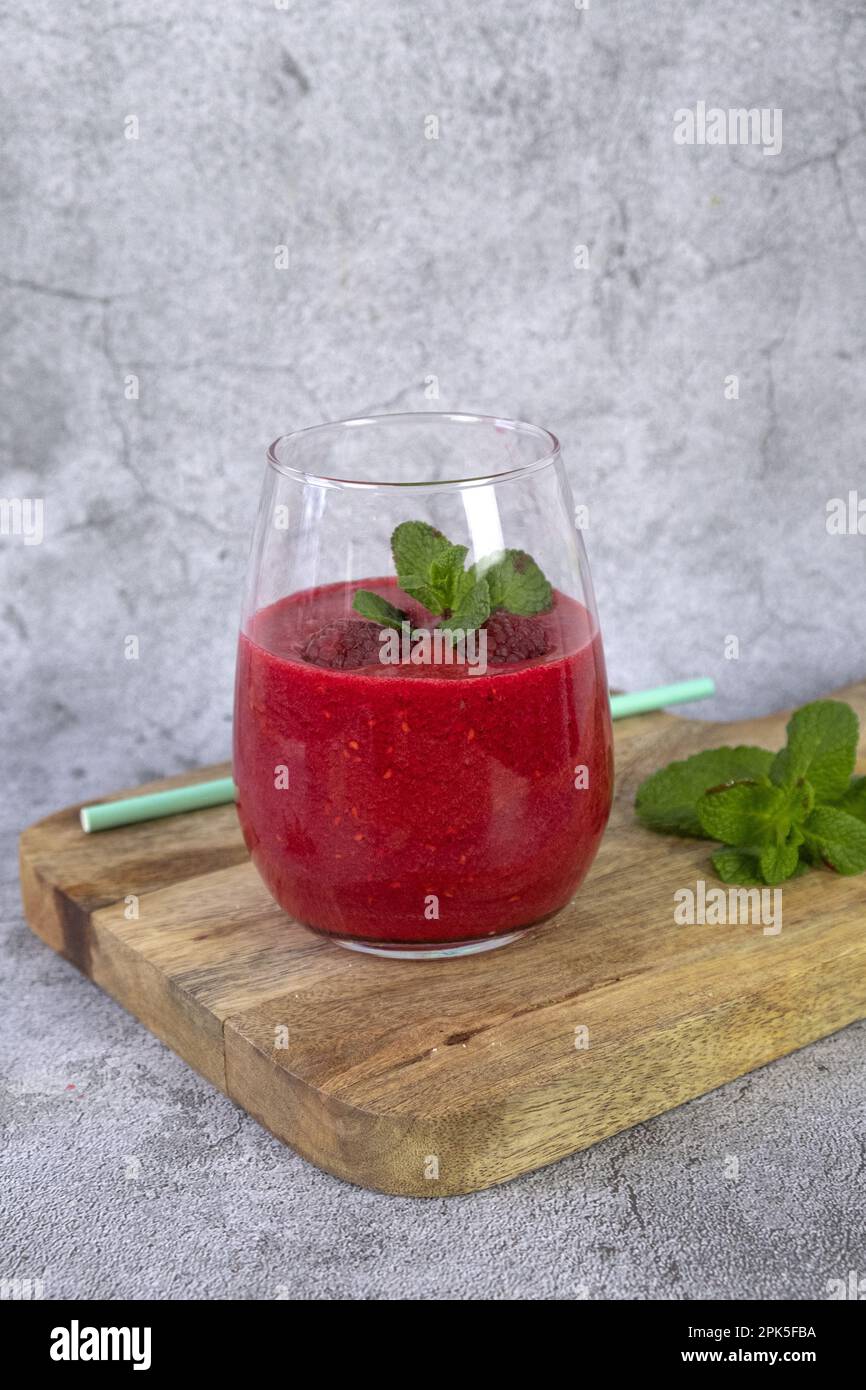 HimbeerSmoothie garniert mit frischem Obst und Minze. Vertikales Foto Stockfoto