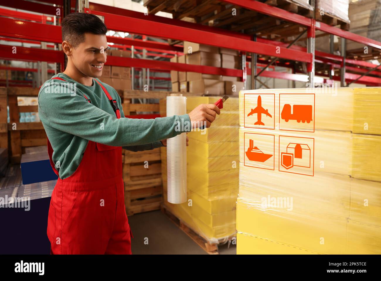 Arbeiter verpackt Kartons mit Versandsymbolen in Stretchfolie im Lager Stockfoto