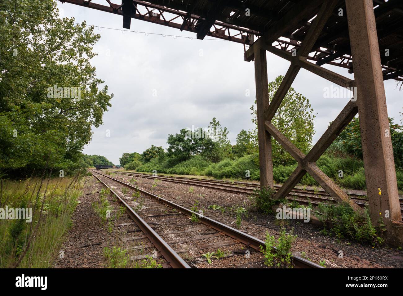 Eisenbahngleis im Eisenbahnhof unter verlassener Brücke Stockfoto