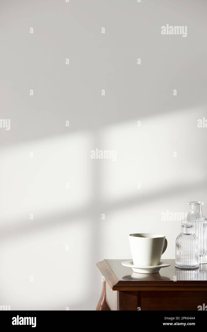 Ein Raum mit einer ruhigen Atmosphäre, mit Tontöpfen vor der Wand und Vorhängen, die Tageslicht hereinlassen. Glasflaschen, Kaffee und verschiedene ob Stockfoto