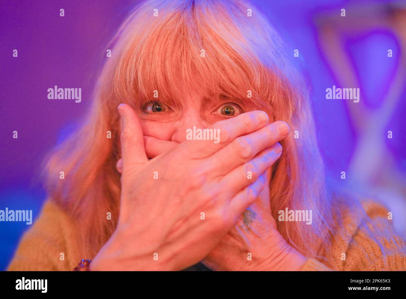 Eine Frau mit Händen über dem Mund, die Überraschung ausdrückt Stockfoto